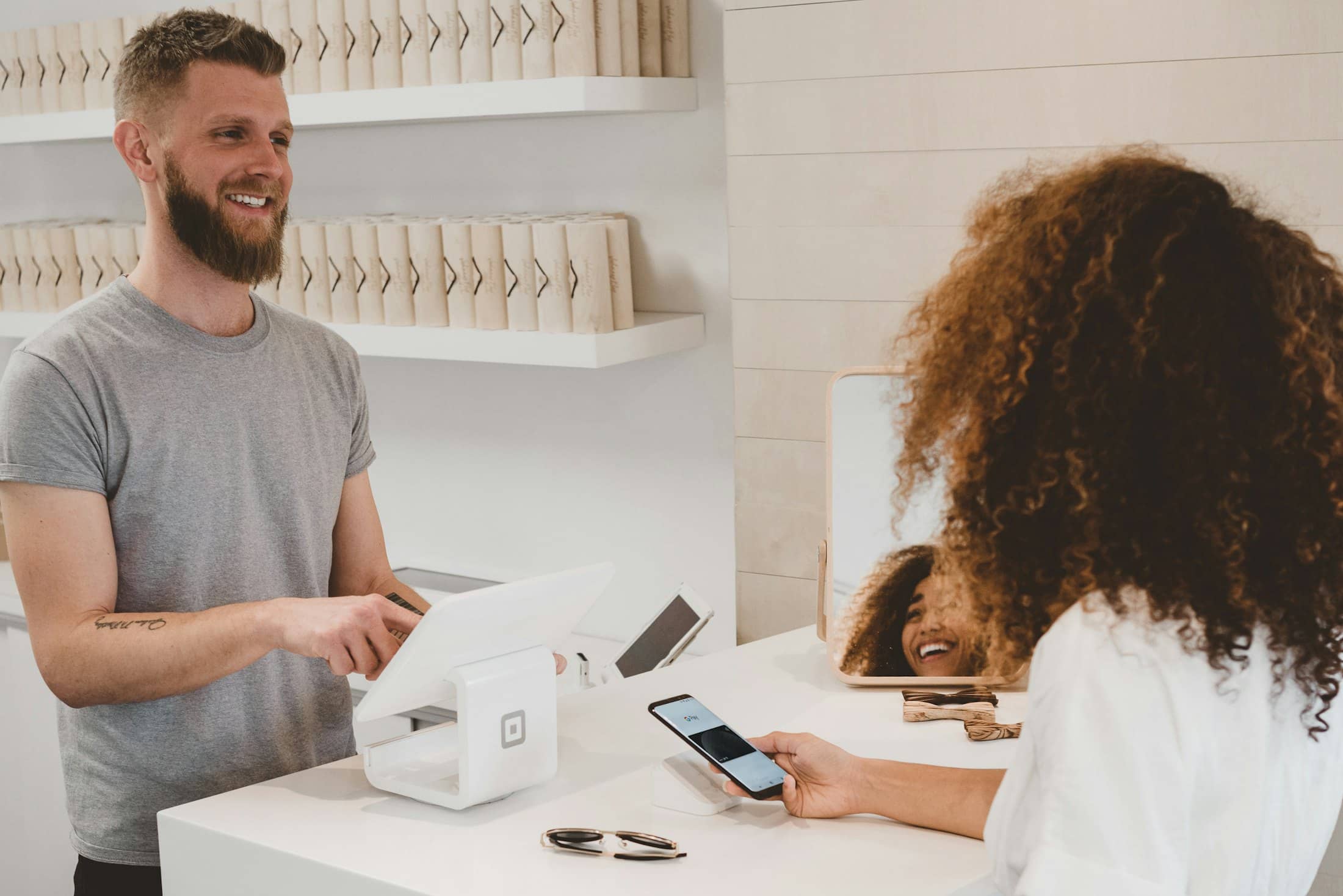 A guest paying by phone at a restaurant counter while the cashier watches the till