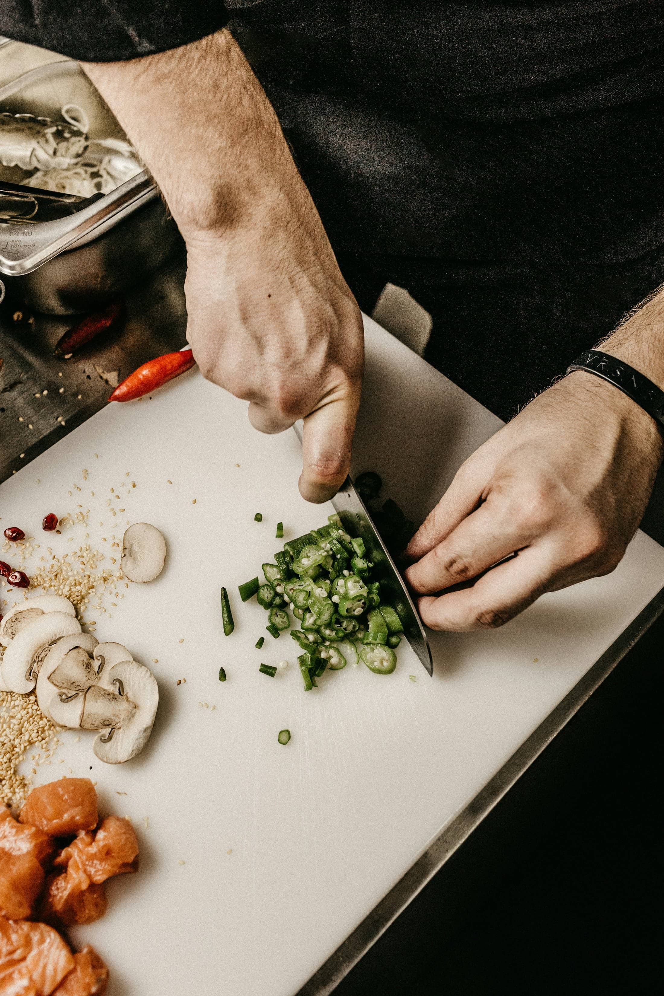 A cook slicing fresh herbs and onions on a chopping board